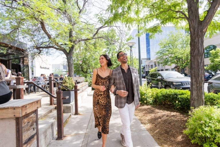 A man and woman walking arm in arm down a sidewalk